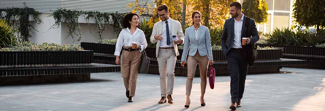 professionals walking on street with sit out area in the background