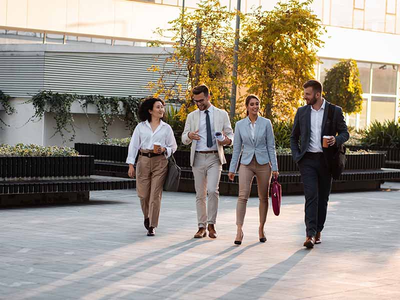 professionals walking on street with sit out area in the background