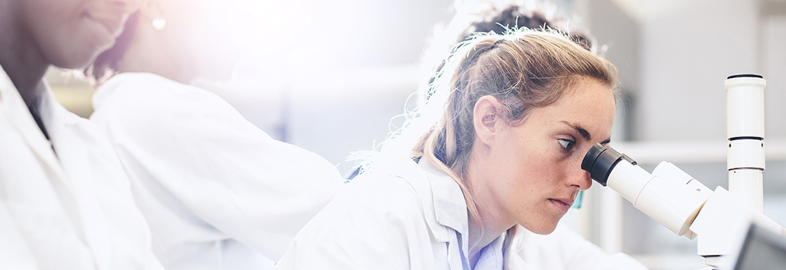 A woman focuses on a microscope