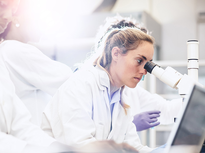 A woman focuses on a microscope