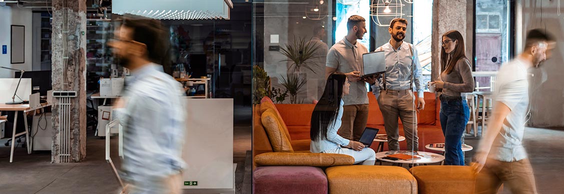 Employees collaborating together in more informal casual office setting with sofa