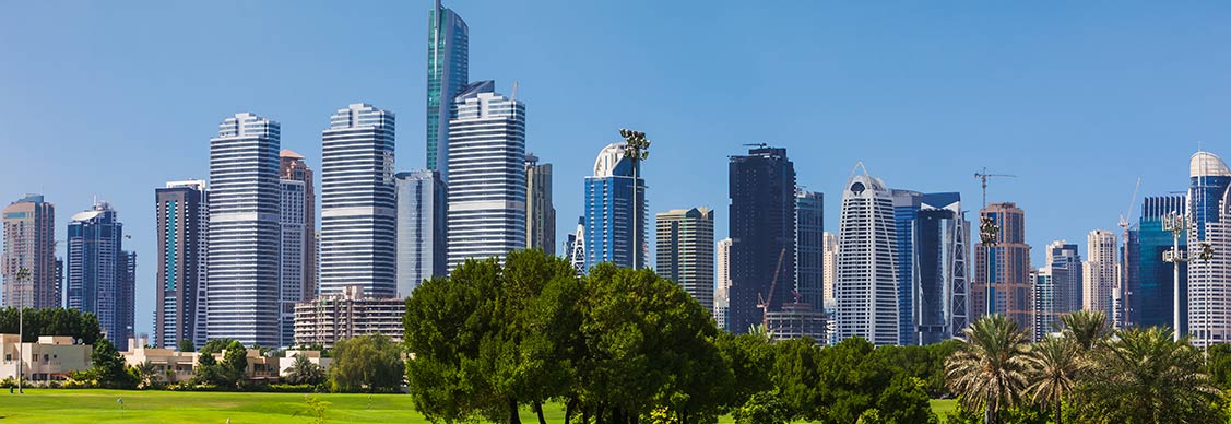 A lush golf course set against a backdrop of towering buildings, illustrating the contrast between greenery and urban life.